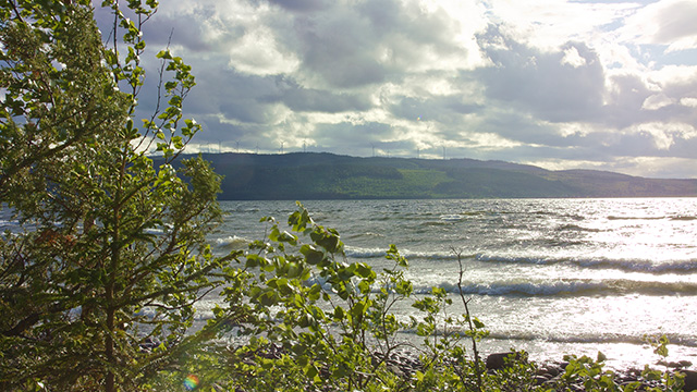 A view over a lake with with a hill in the background and a cloudy sky shoot under the midnight sun